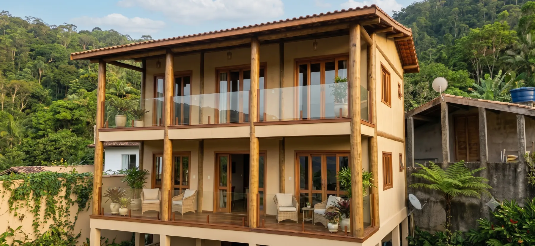 Casa de dois andares com pilares e estrutura em eucalipto tratado, cercada de mata atlântica